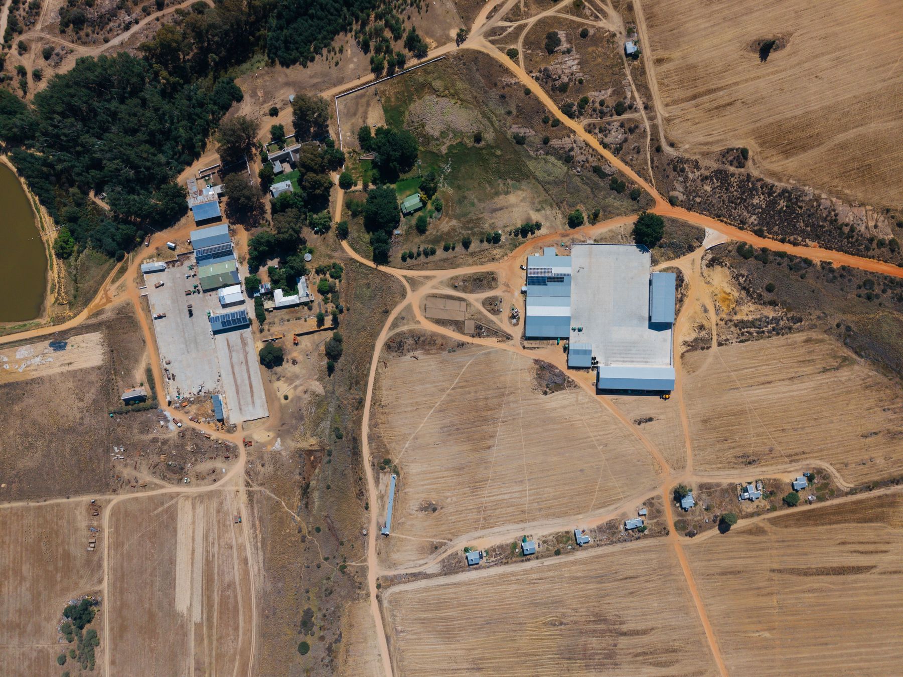 Aerial view of a farmyard with sheds, trees and surrounding fields