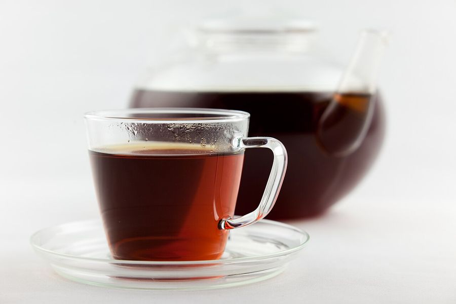 A glass teapot and cup of freshly brewed amber-red rooibos